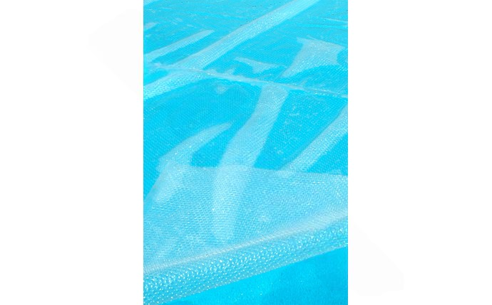 Solar cover in use on a backyard swimming pool